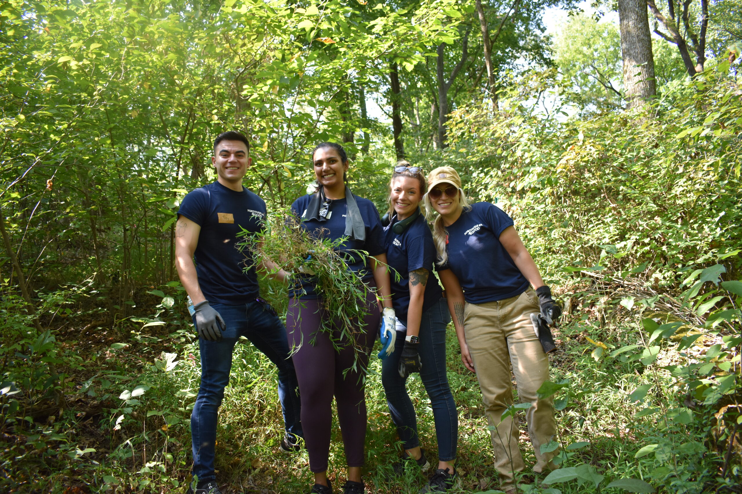 Four colleagues standing together in a wooded area.